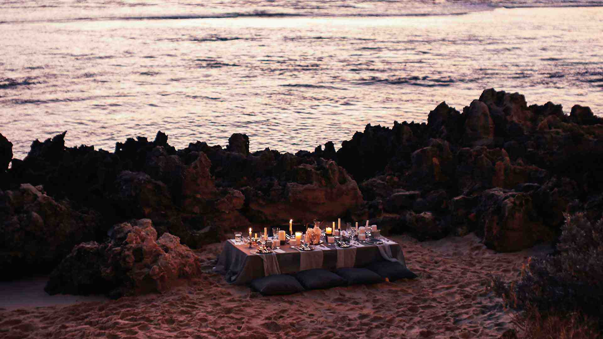 Candlelit bespoke dinner set up on a beach front.