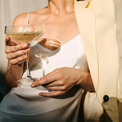 Women in chic clothing holding a glass of champagne