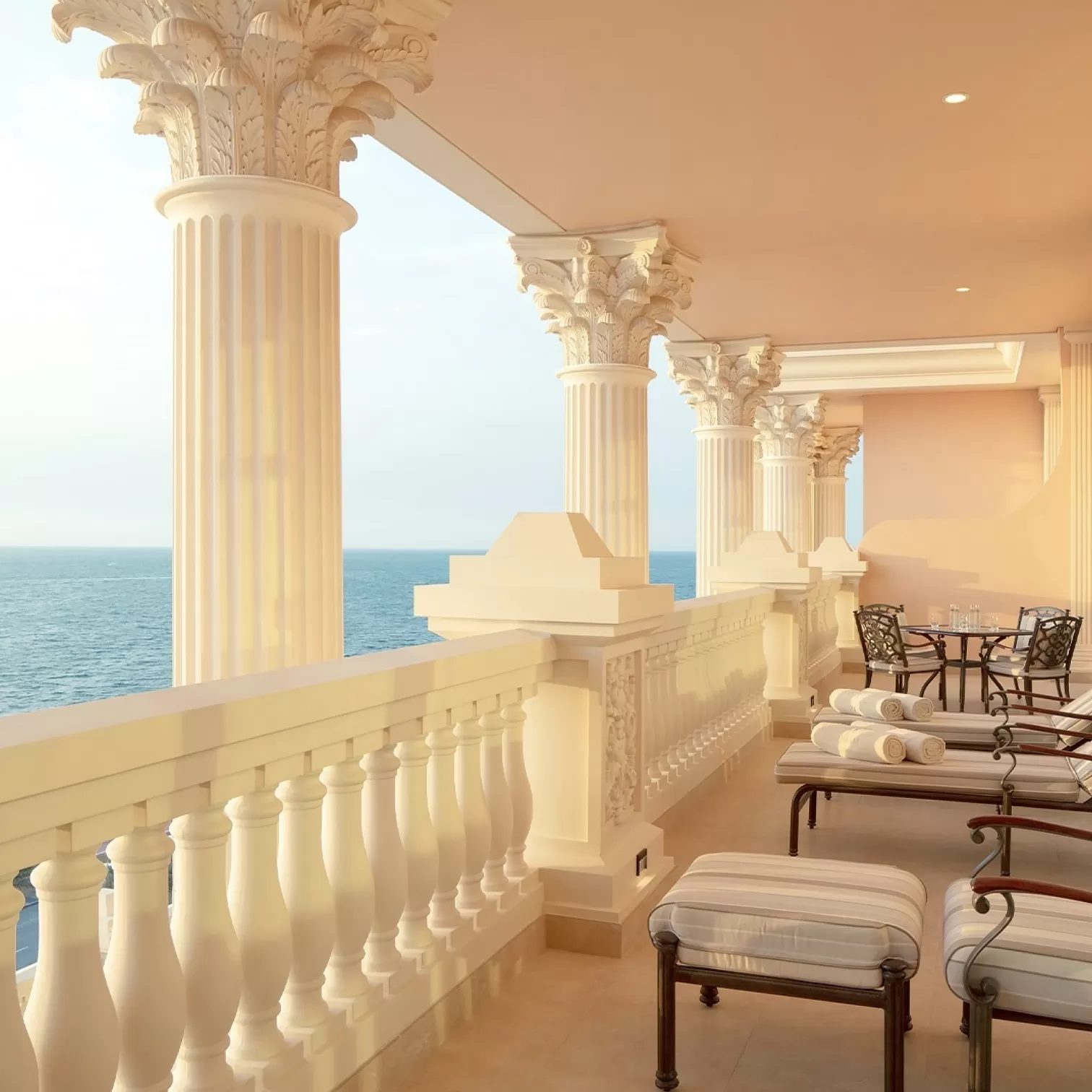 Luxurious white long balcony with sunbeds overlooking the sea, Raffles, Palm Dubai
