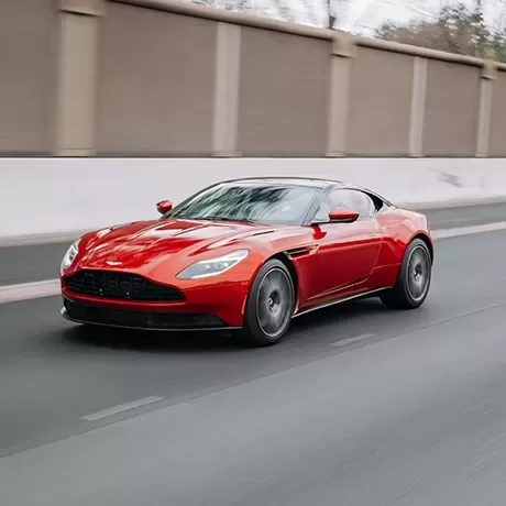 Red Aston Martin sports car driving on the road