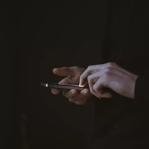 Dark photo of person holding iPhone
