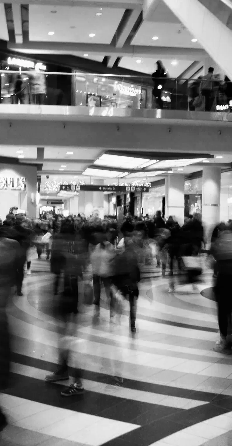 Back and white photo with long exposure of people walking through a shopping centre