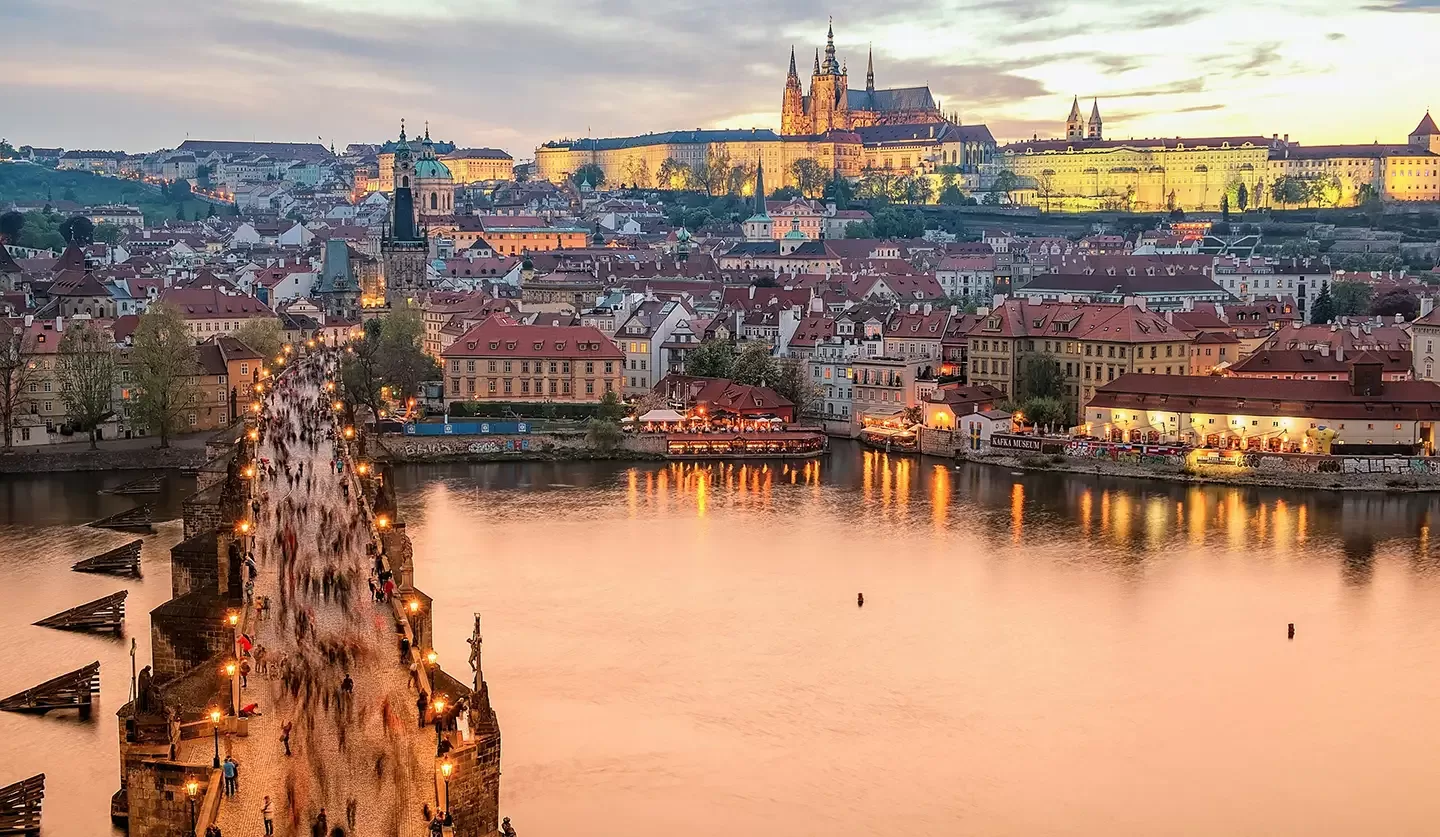 The iconic Charles Bridge in Prague, Czech Republic, adorned with statues and bustling with visitors against a scenic backdrop.