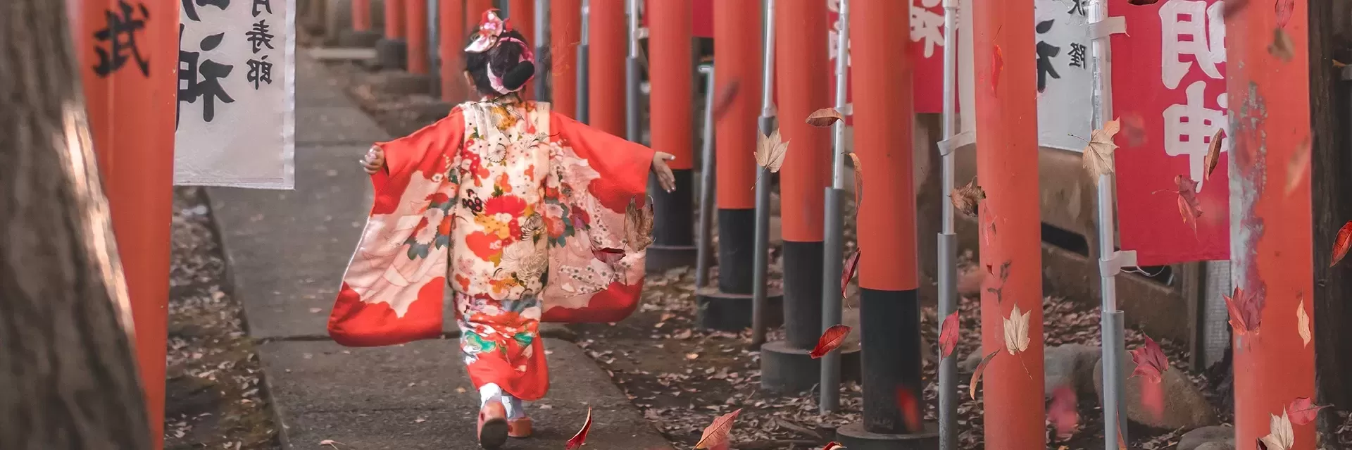 Little girl in traditional Japenese dress running with her hands out along a pathway