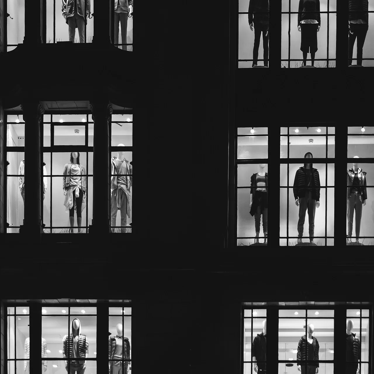 Black and white photo of window display of mannequins wearing men and women's fashion