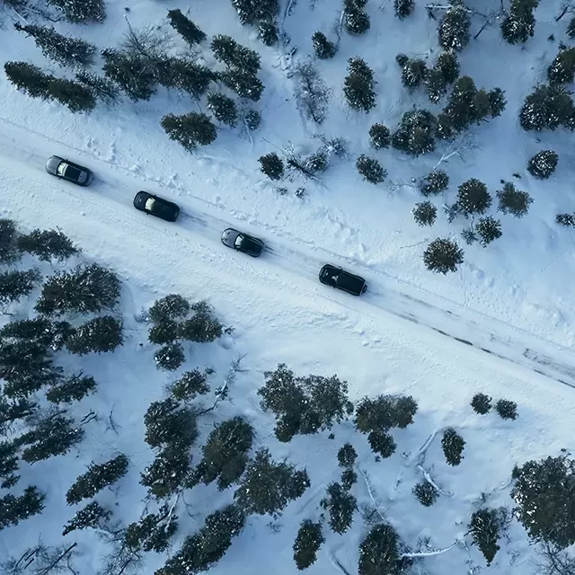 Birds eye view of Jaguar and Land Rover cars driving through snowy road
