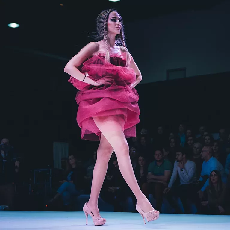 Model in pink couture dress walking down the runway