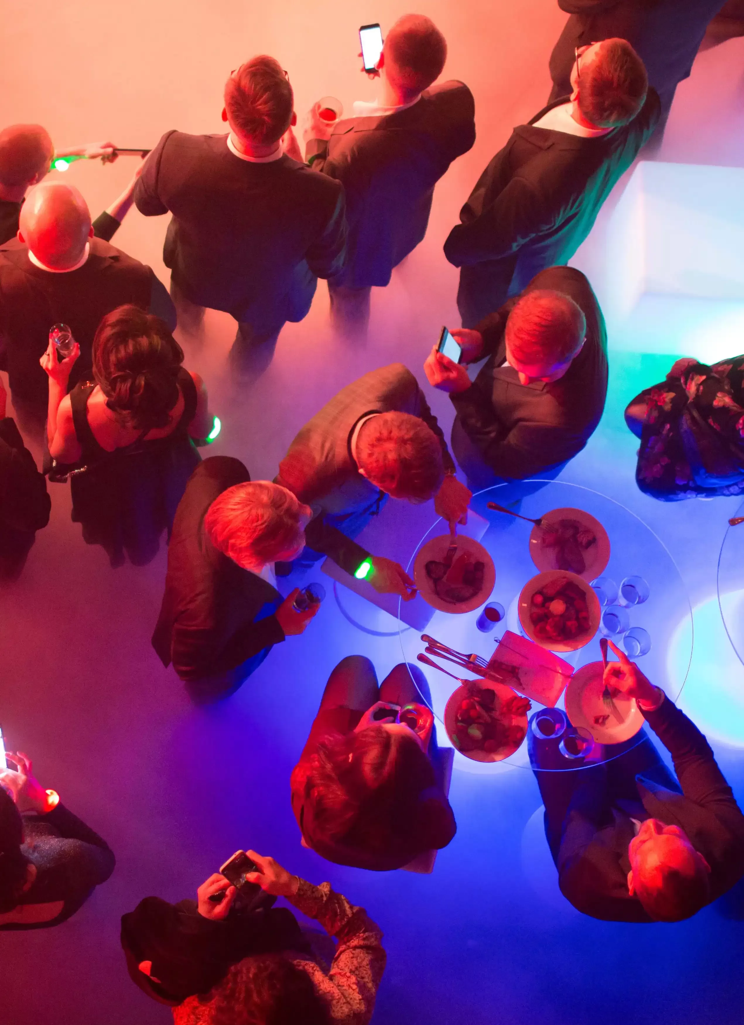 Group of people in suits drinking in a club with colorful lights