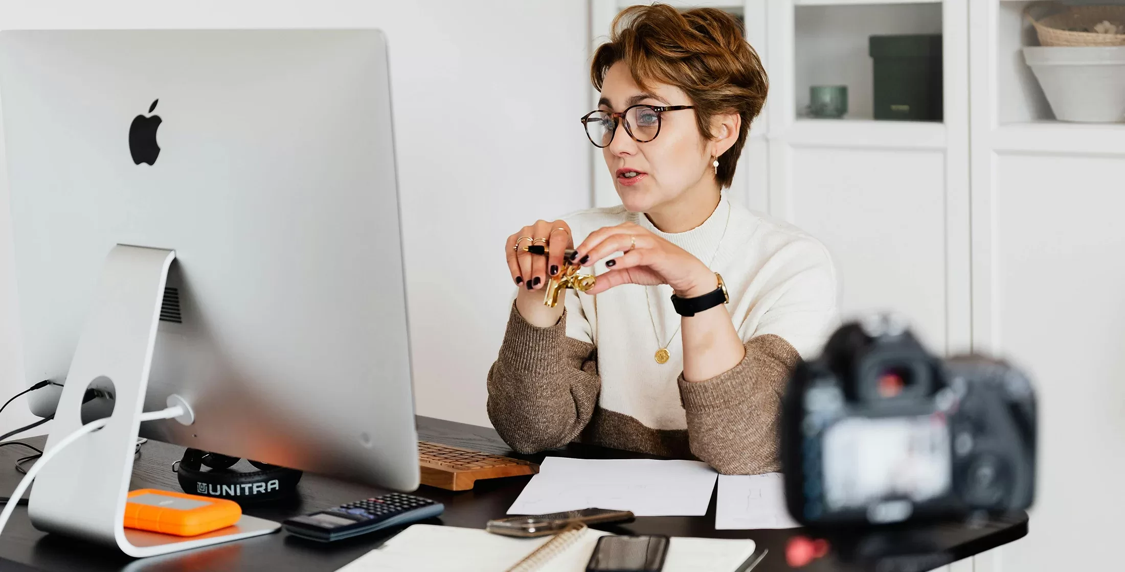 Women sat at her desk with an iMac, recording herself talking