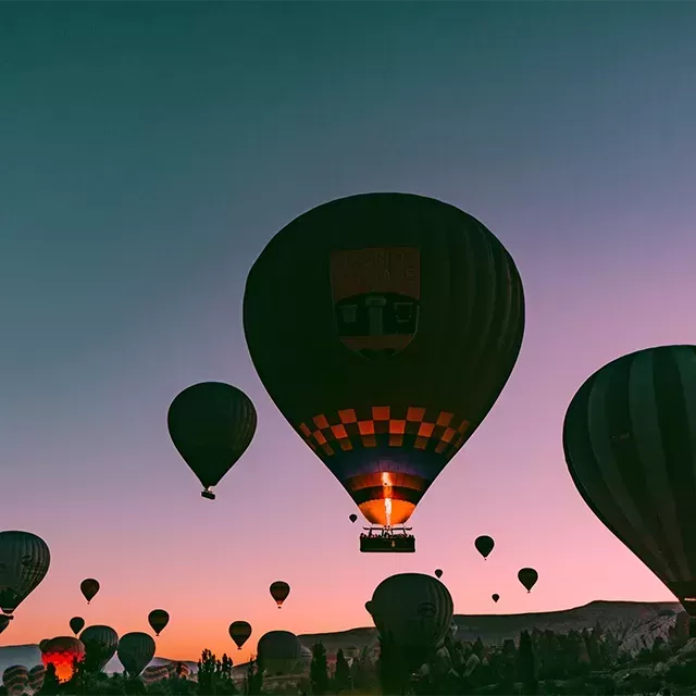 Pink and blue sky at nighttime filled with hot air balloons