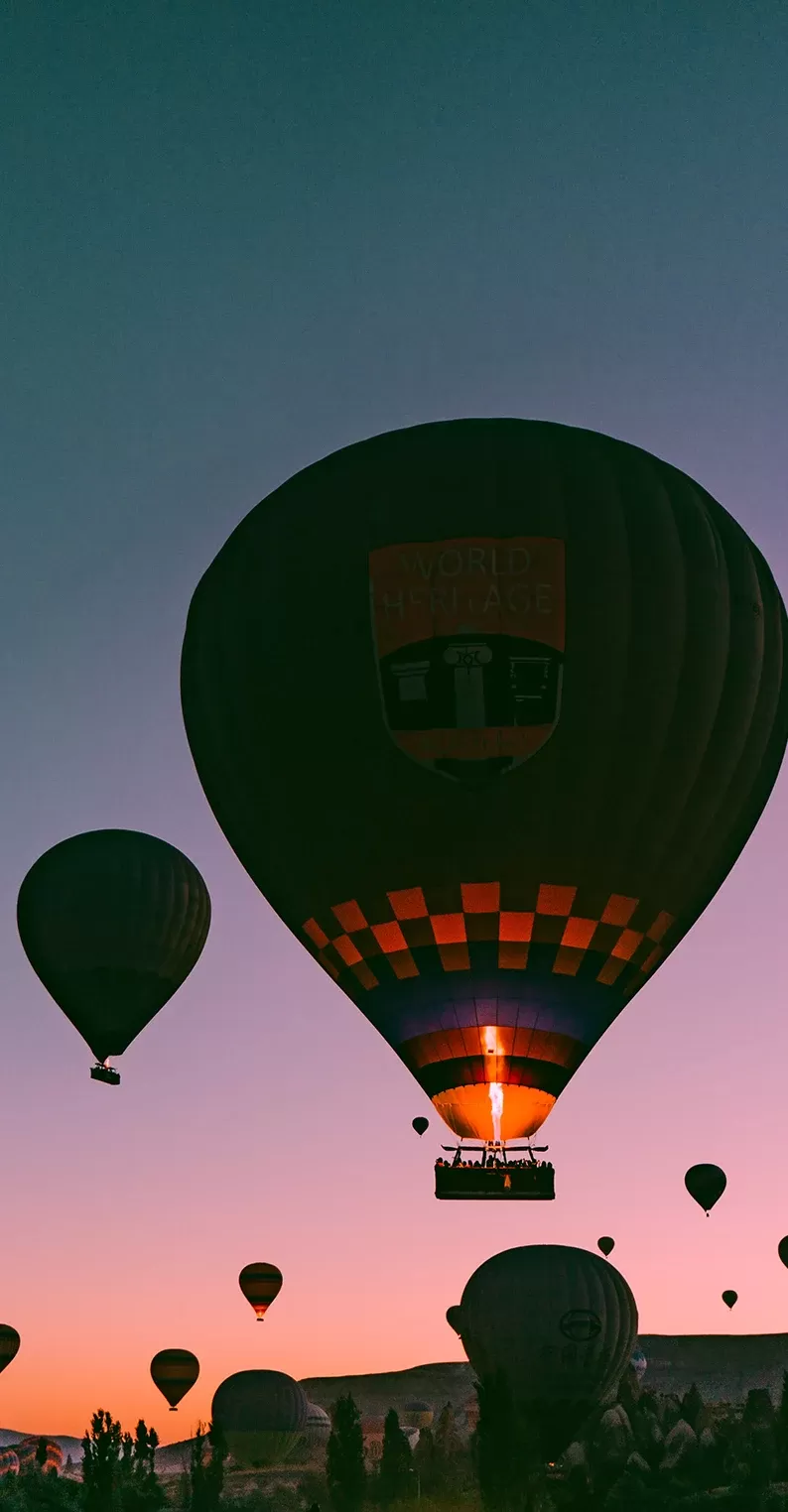 Pink and blue sky at nighttime filled with hot air balloons