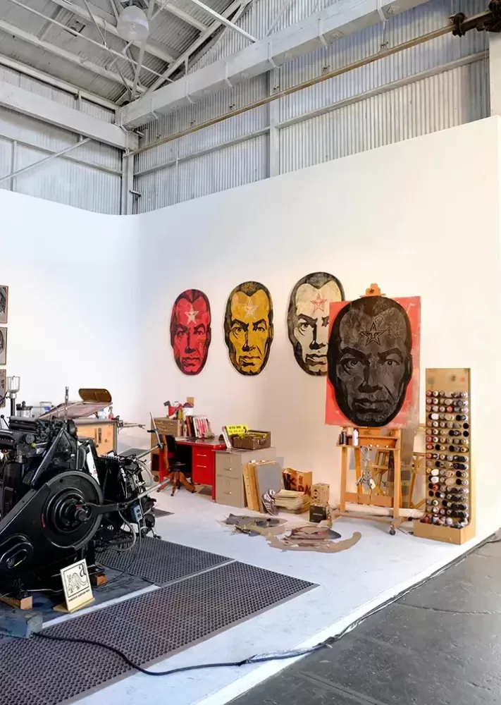 A spacious room featuring a large machine alongside an array of colorful paintings adorning the walls.