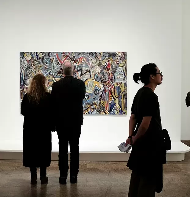 Attendees admiring an art exhibit, surrounded by captivating pieces in a museum environment.