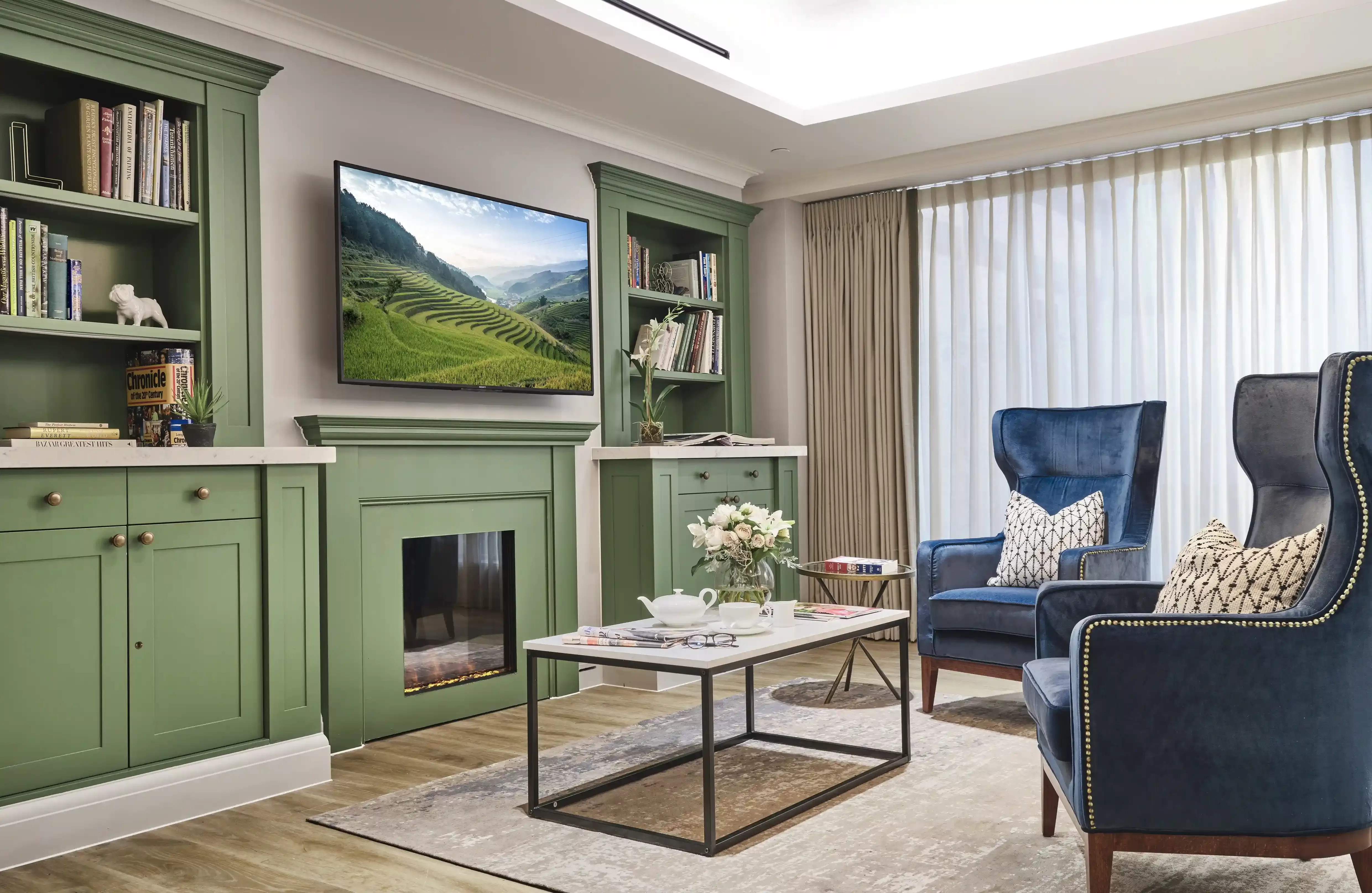 Lounge with two blue armchairs, green TV unit, bookshelf and TV