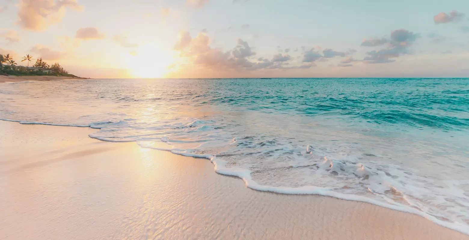 Beautiful sandy beach with clear blue skies, soft waves and sunset sky,