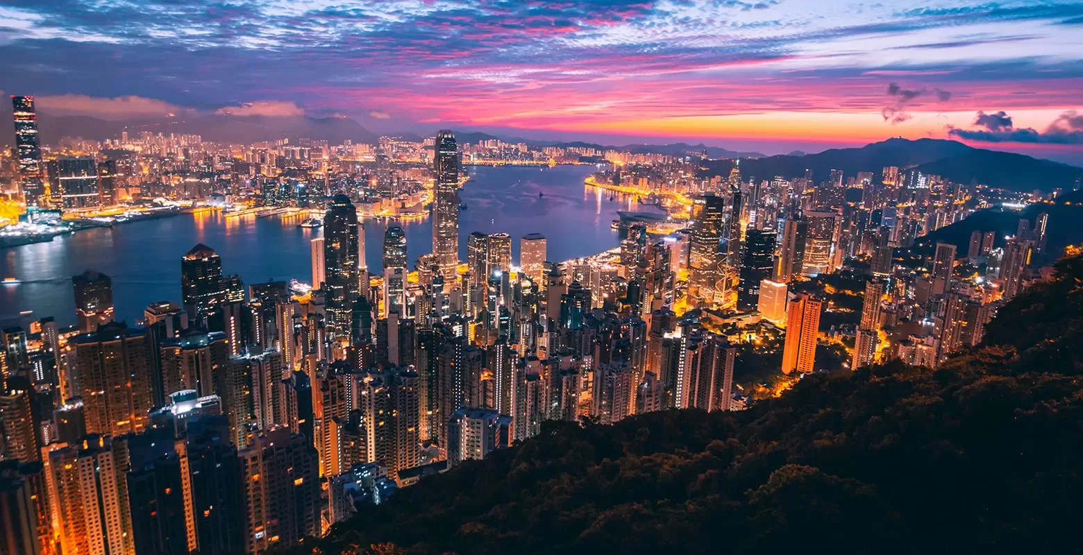 A stunning view of the Hong Kong skyline illuminated by the warm hues of sunset, showcasing iconic skyscrapers against the sky.