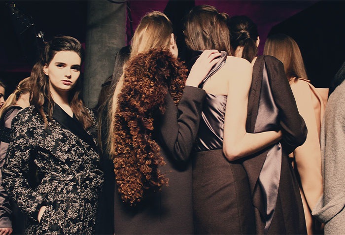 Models wearing fashion preparing to walk on a catwalk
