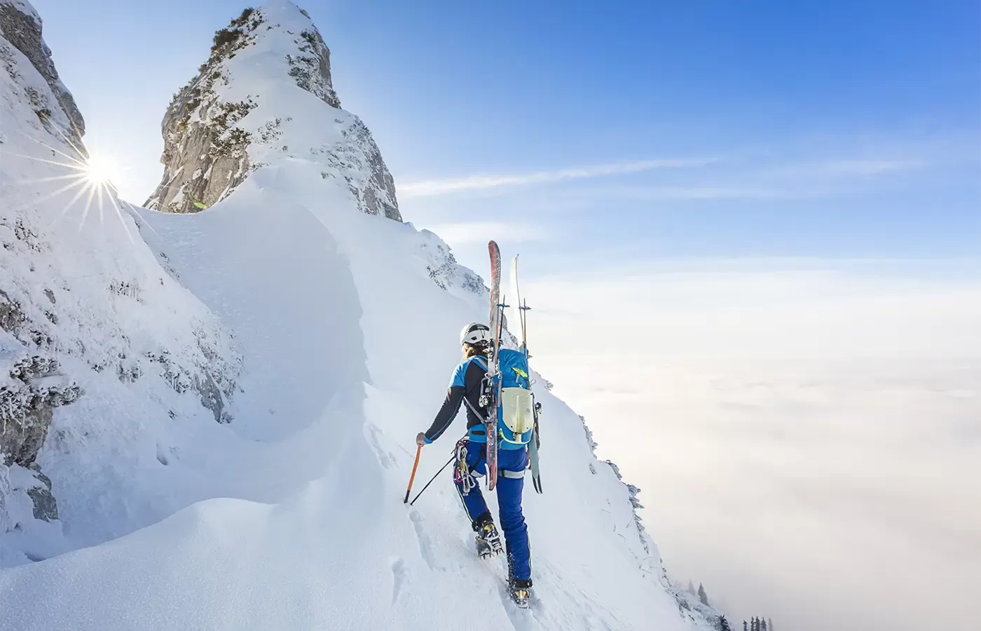 Person with ski gear and ski's hiking up snowy mountain in Lofoten Islands, Norway