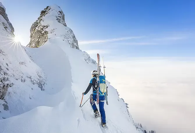 Person with ski gear and ski's hiking up snowy mountain in Lofoten Islands, Norway