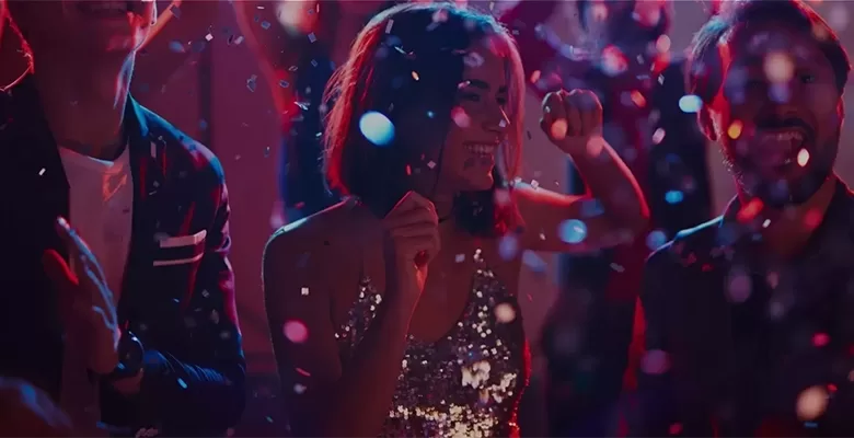 Woman in a sequin dress dancing in the middle of a dance floor in the middle of falling confetti.