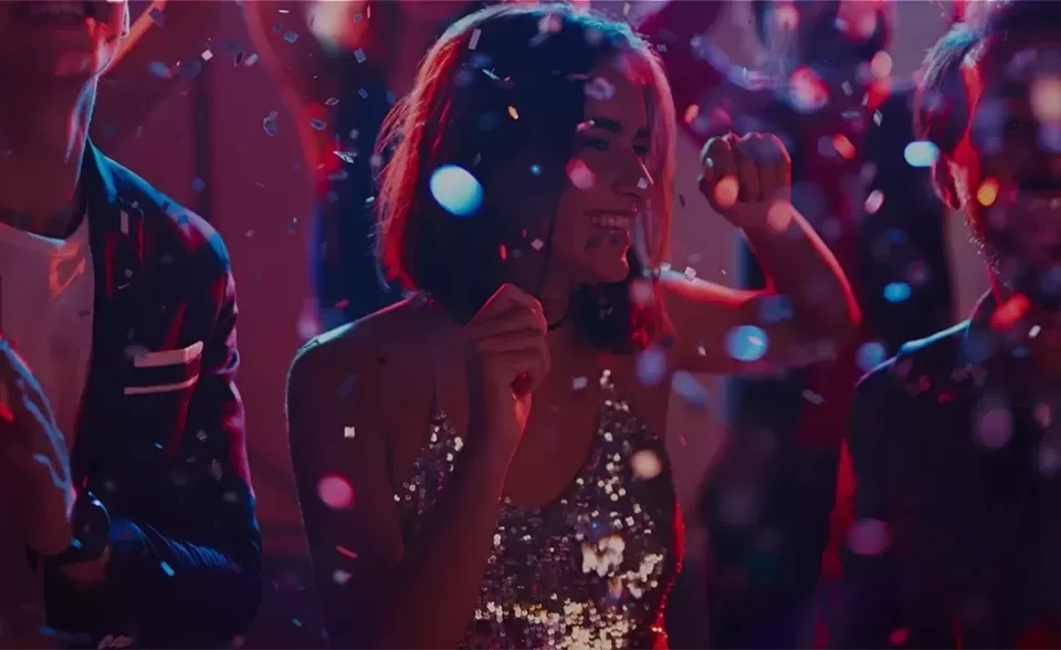 Woman in a sequin dress dancing in the middle of a dance floor in the middle of falling confetti.