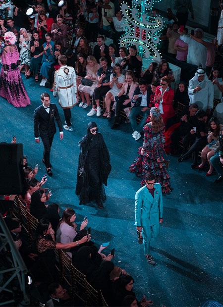 Models walking down catwalk runway in front of seated audience at London Fashion Week