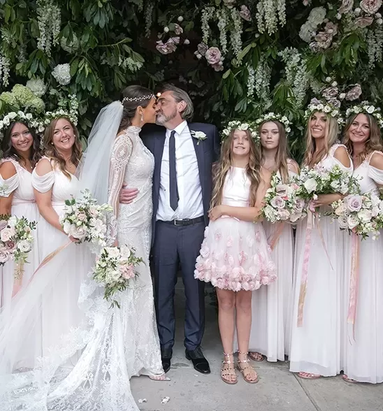 Bridge and groom kissing next bridesmaids holding flowers | Quintessentially Weddings
