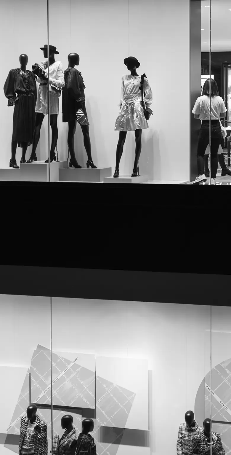 Black and white photo of window display of mannequins wearing women's fashion