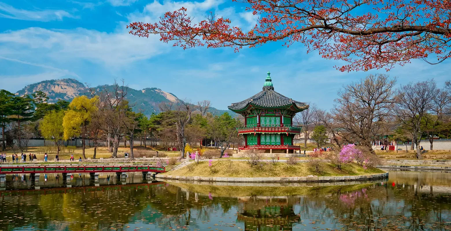 A picturesque pagoda perched on a small island within a calm pond, framed by vibrant foliage in Seoul, South Korea.