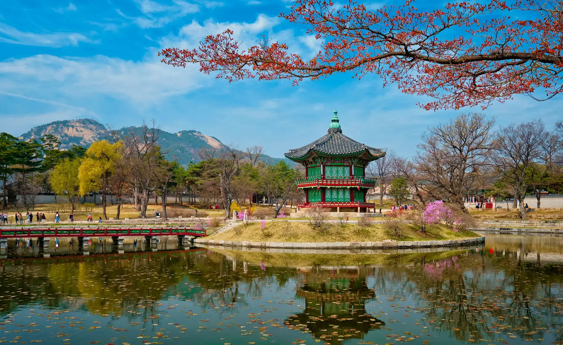 A picturesque pagoda perched on a small island within a calm pond, framed by vibrant foliage in Seoul, South Korea.