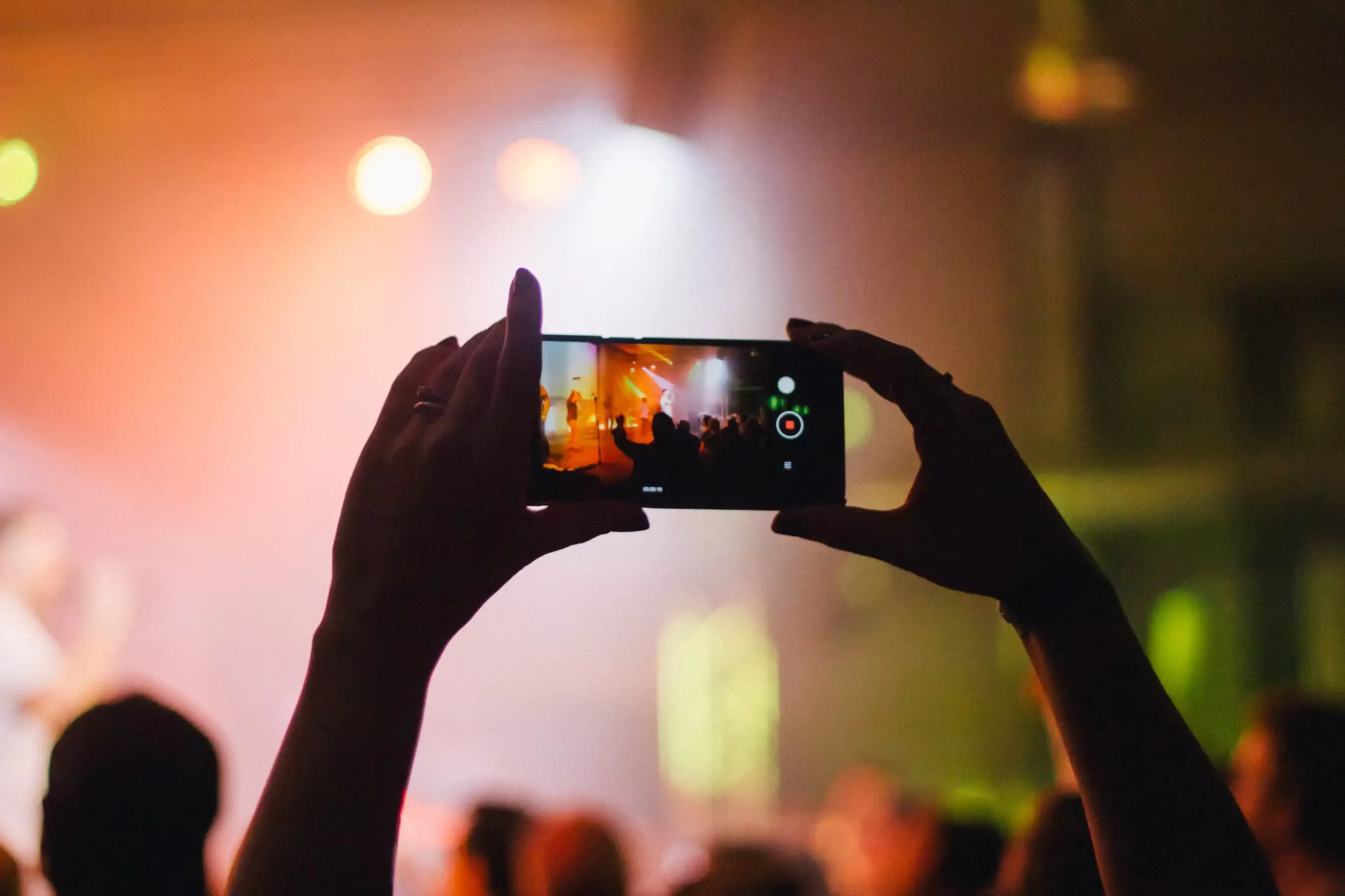 Person holding up iPhone to take picture at a gig