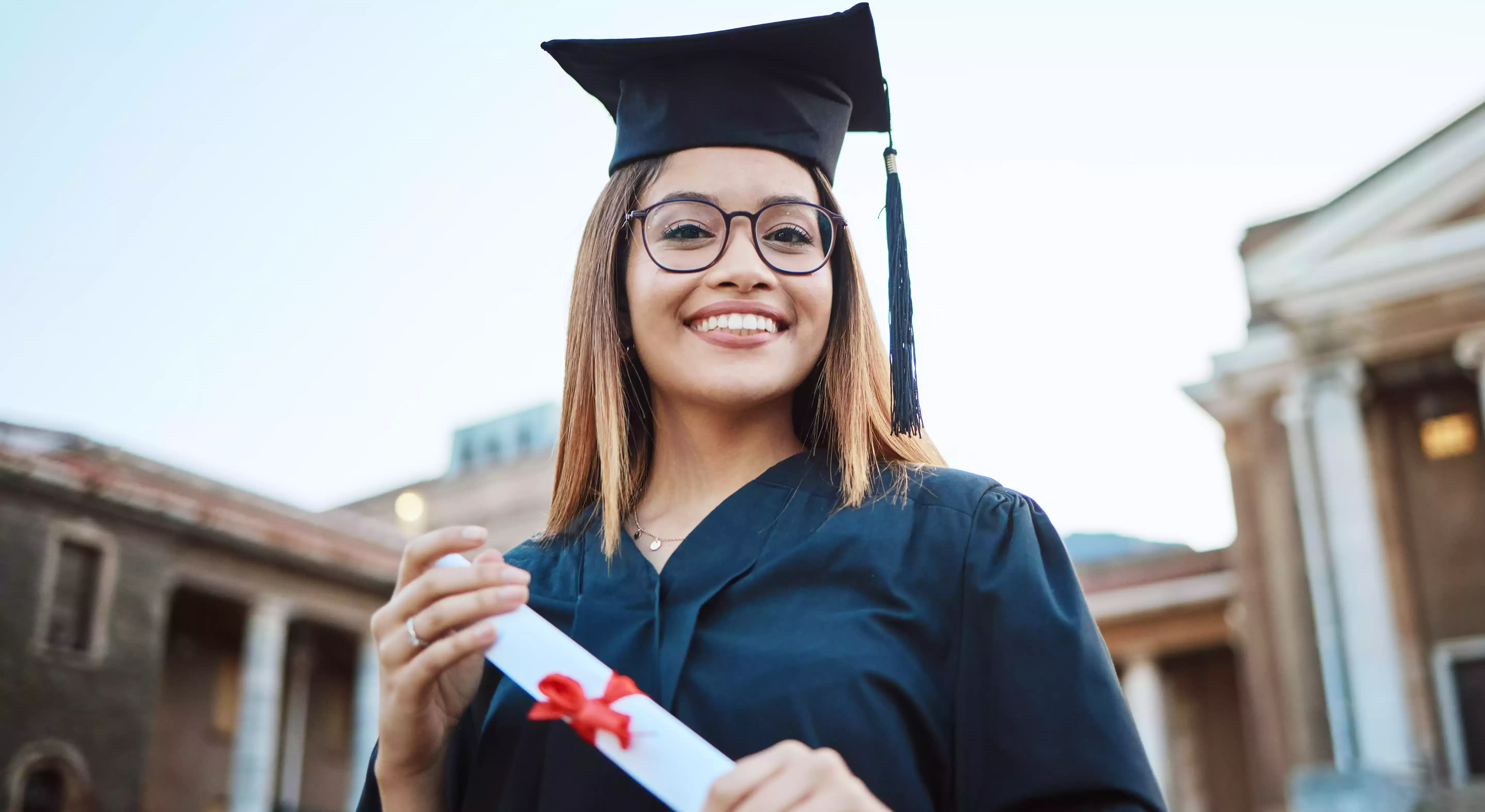 Woman in graduation robe and gown holding a scroll
