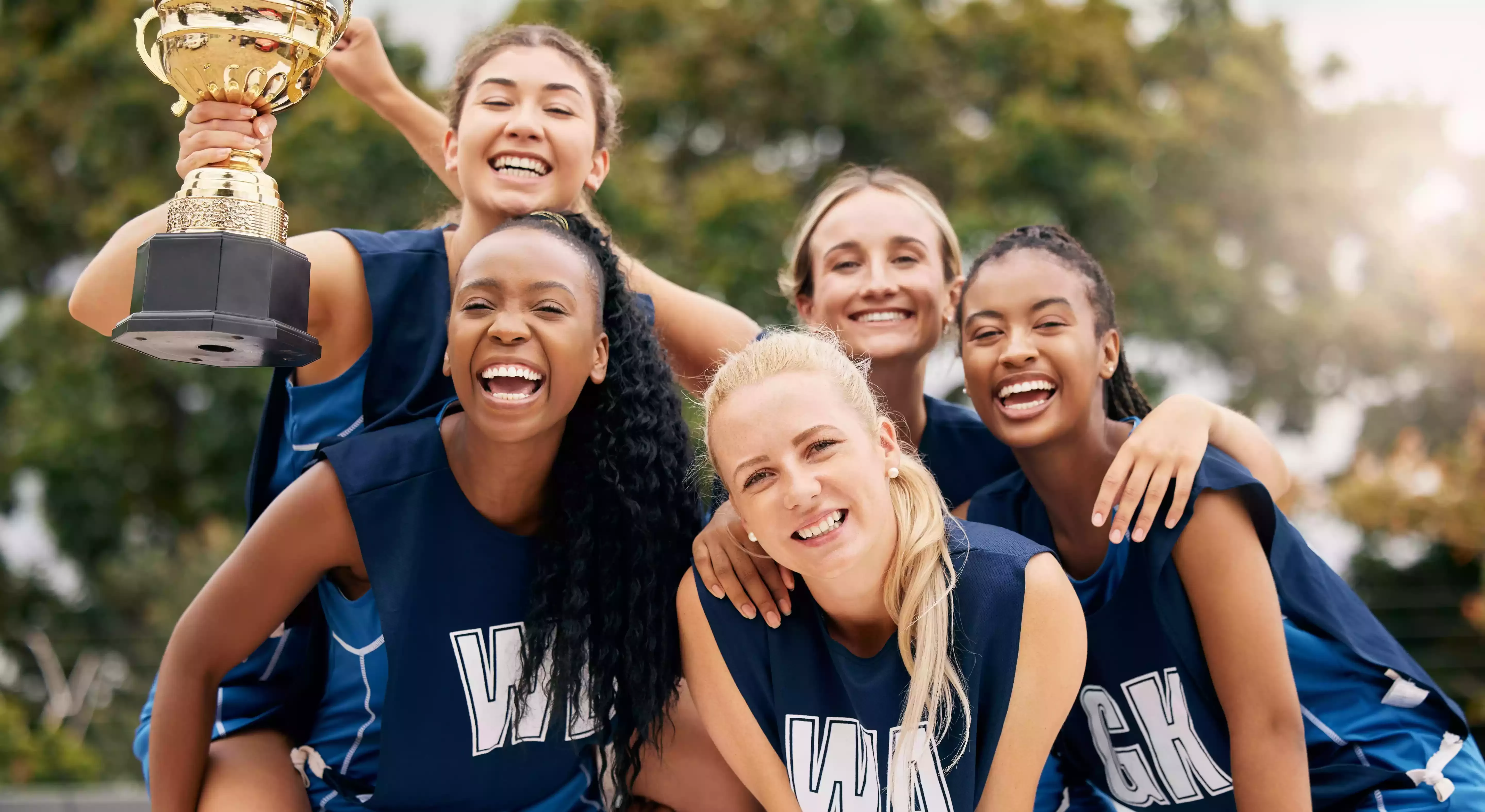 Group of girls sport team celebrating a trophy win, US colleges
