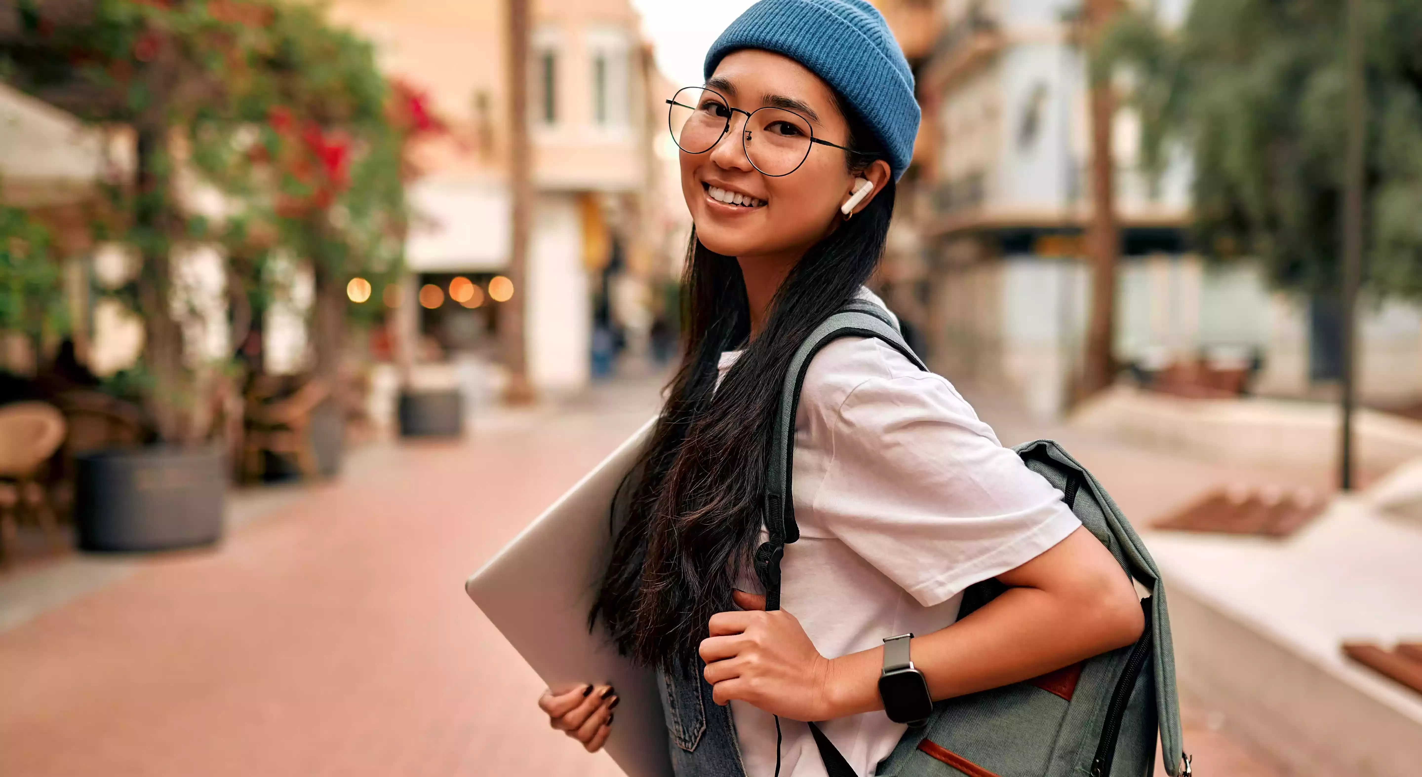 Girl travelling study abroad abroad carrying rucksack and laptop walking down a rustic street