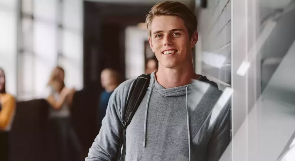 Student in school wearing rucksack and smiling, US