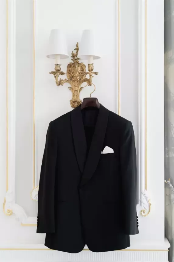 Suit jacket hanging off gold wall lamp shape.