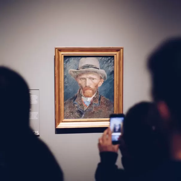 People viewing and taking photos on their smartphones of Vincent Van Gogh self-portrait  hanging on the wall at a gallery