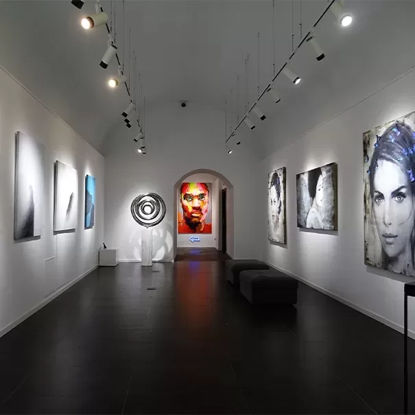 Art gallery with white walls and arches doorway with modern portrait art pieces hanging on the wall