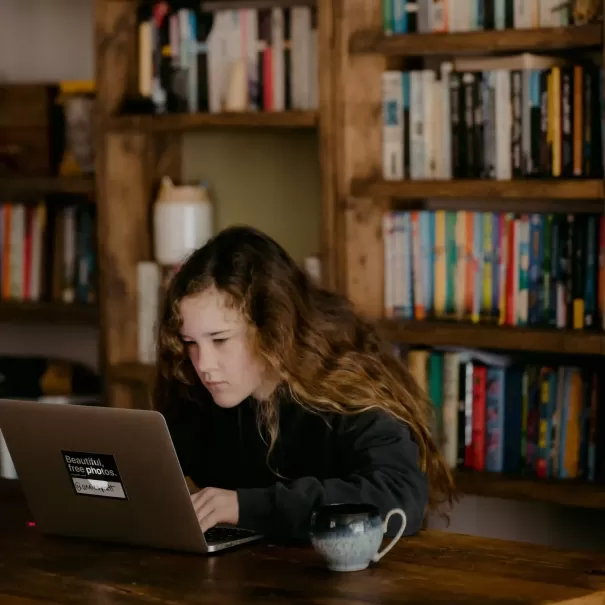 Girl on a computer sat in front of book shelf