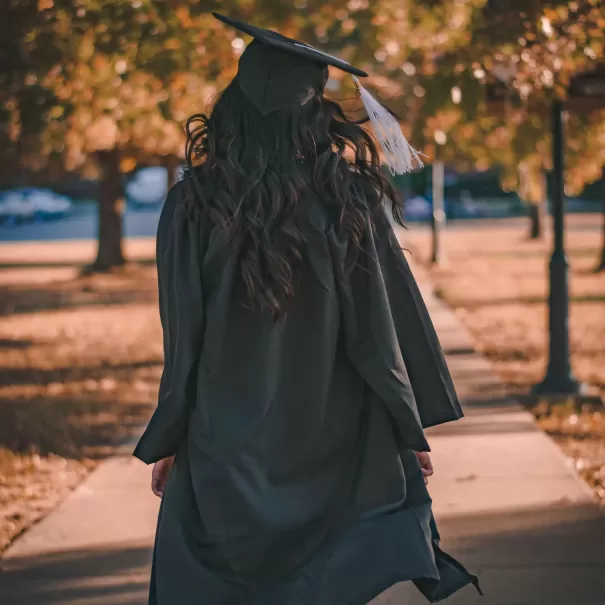 Women wearing graduation cloak and hat walking down a path