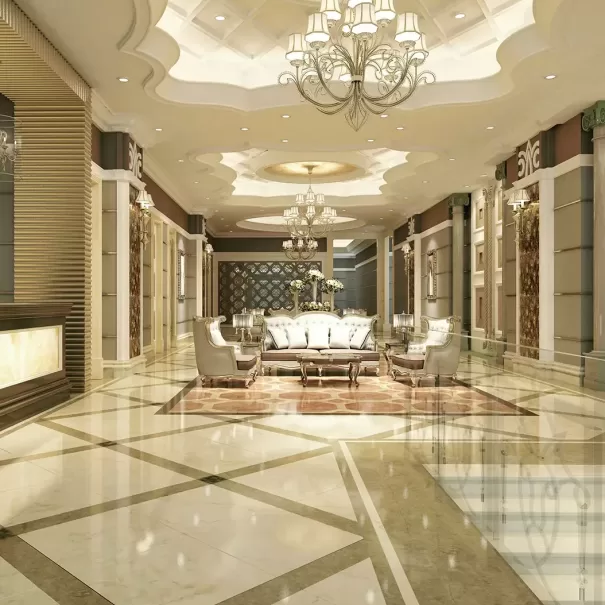 Elegant hotel lobby with polished marble floors, ornate chandeliers, plush white sofas, and gold accents. The ceiling features intricate molding and recessed lighting, creating a luxurious and welcoming atmosphere.