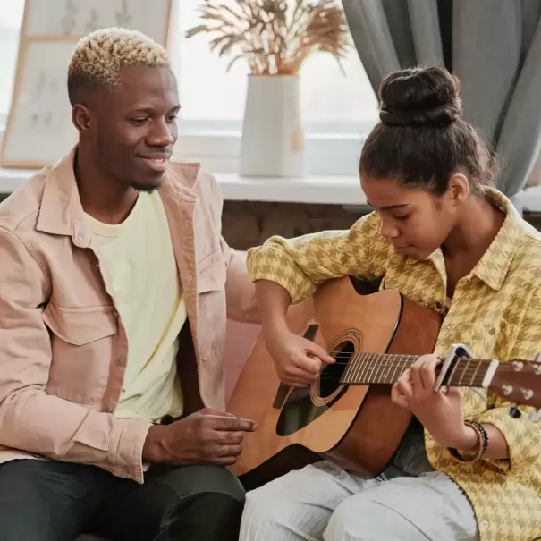Man smiling siting with women playing guitar