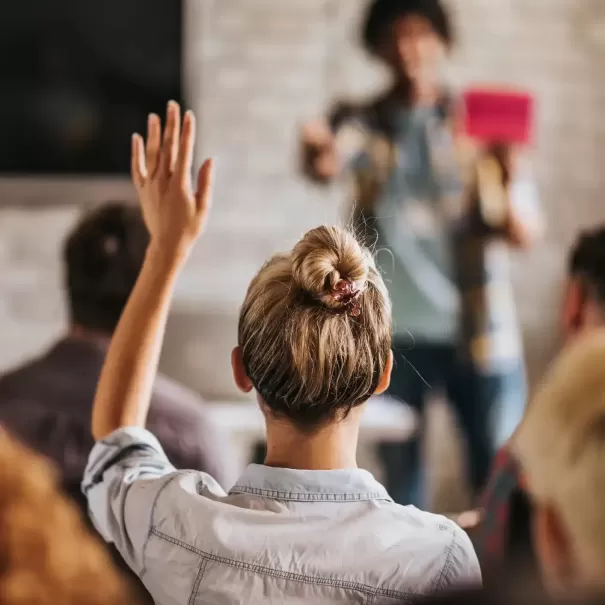 Back of women raising her hand up in class