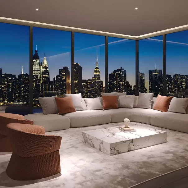 A modern living room with a large white sectional sofa, brown accent chairs, and a marble coffee table, featuring floor-to-ceiling windows overlooking a city skyline at dusk.