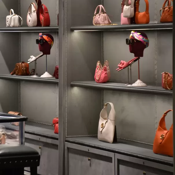 Visual merchandise display of a grey open cabinet and shelving displaying colourful accessories and handbags in a boutique.