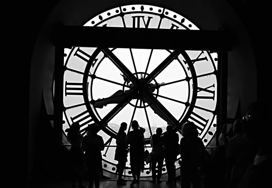 Black and white picture of people standing in front of large vintage clock face