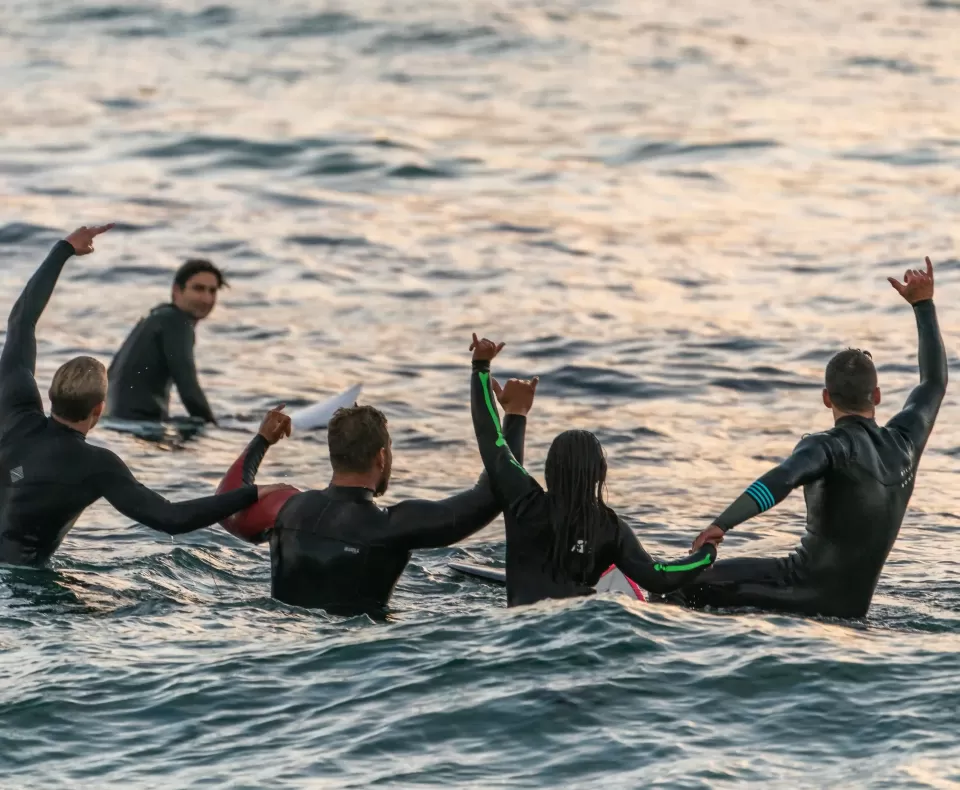 Group pf people in wetsuit celebrating in the sea