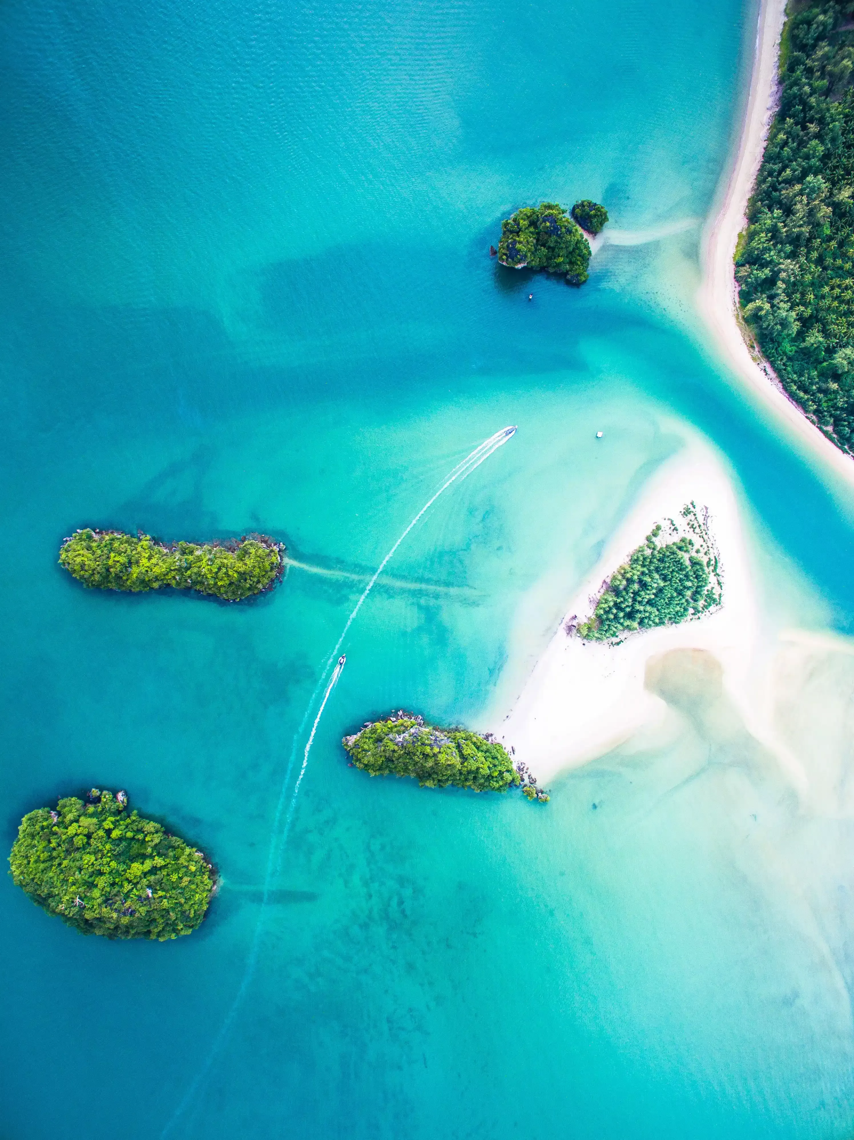 Birdseye view of little islands amongst clear blue sea
