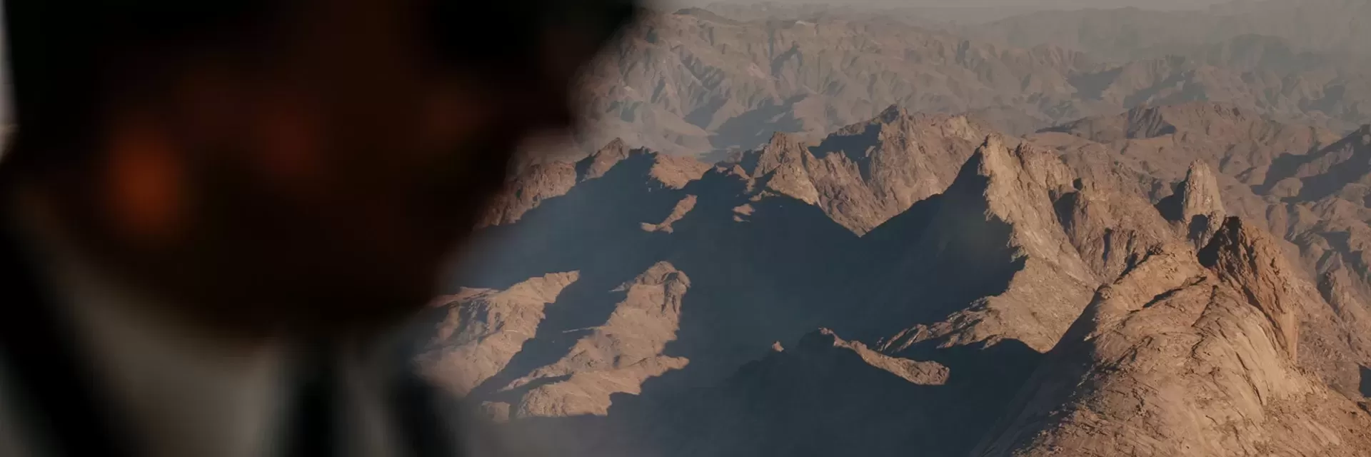 Man in a plane flying over rocky mountains in Alula, Saudi Arabia