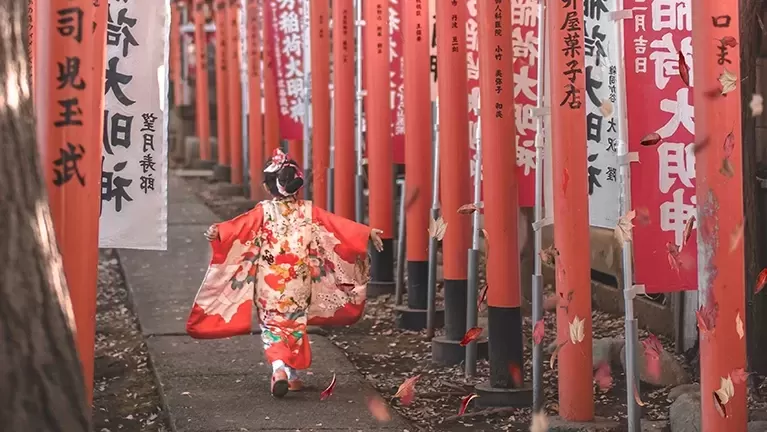 Little girl in traditional Japenese dress running with her hands out along a pathway